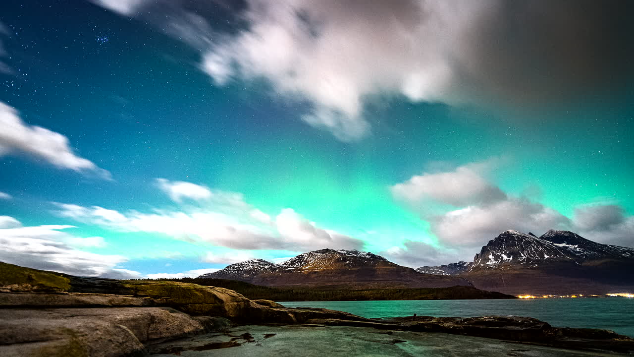 las luces del norte brillan en el cielo por encima de las nubes voladoras en noruega, movimiento de lapso de tiempo