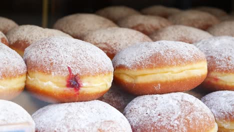 close up view of stacked jelly doughnuts with powdered sugar