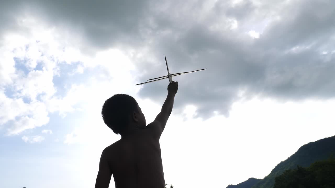 Child playing with toy airplane and kite in the sky