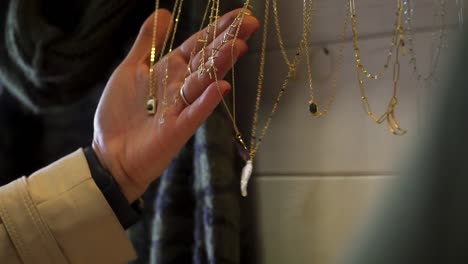 slowmotion close-up shot of a woman browsing the gold jewelry on sale in a shop