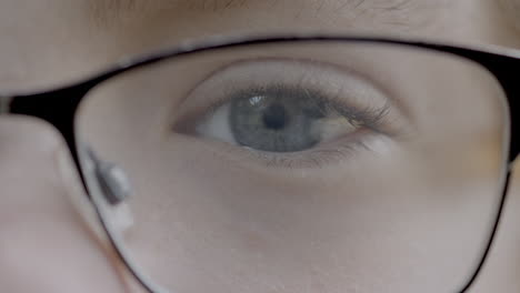 closeup of a child's pretty blue eye and eyelashes behind glasses looking into camera