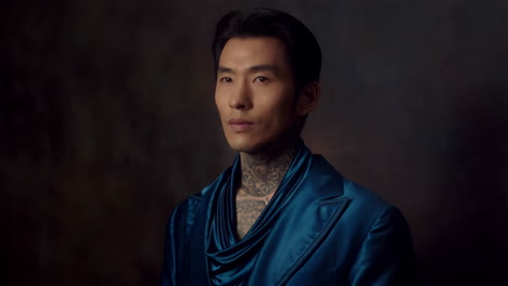 portrait of a man with neck tattoos in a blue jacket