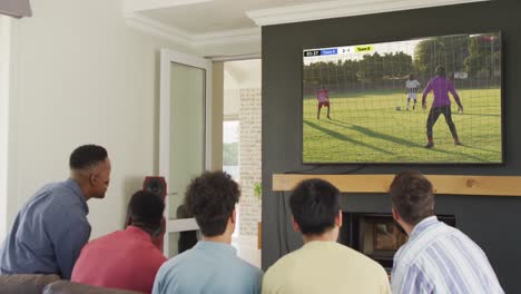 video of diverse friends sitting on sofa and watching football on television at home