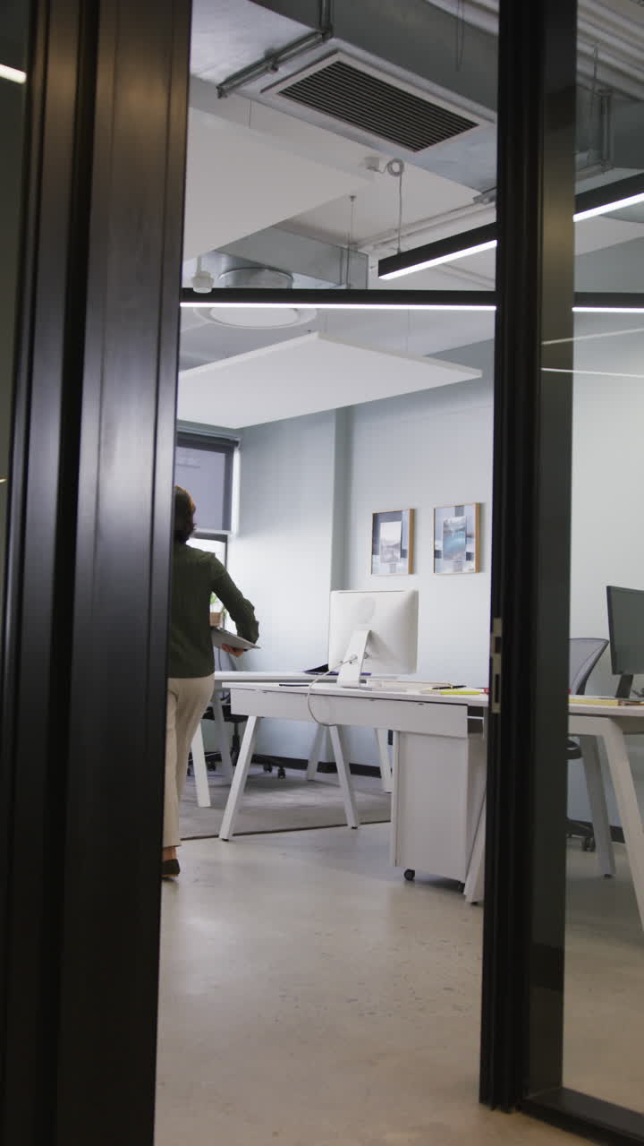 Video verticale di una donna d'affari asiatica che cammina con il portatile in ufficio