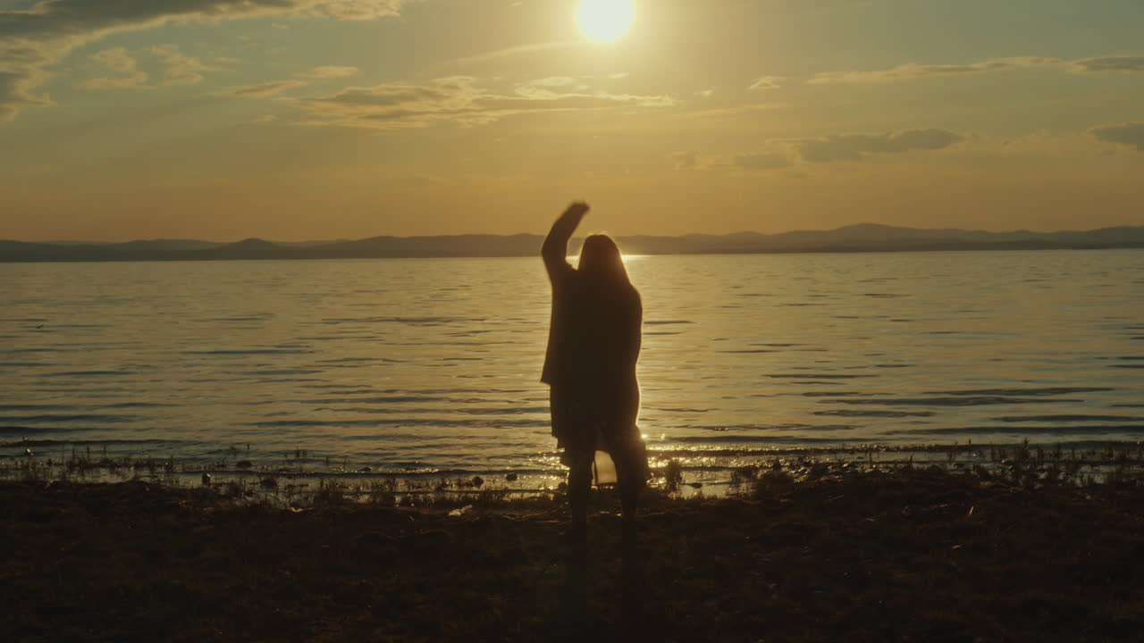 호수 연안 에서 풍경적 인 일몰 을 즐기는 행복 한 여자 의 실루