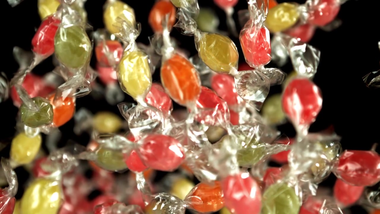 Caramelle incartate colorate che cadono al rallentatore
