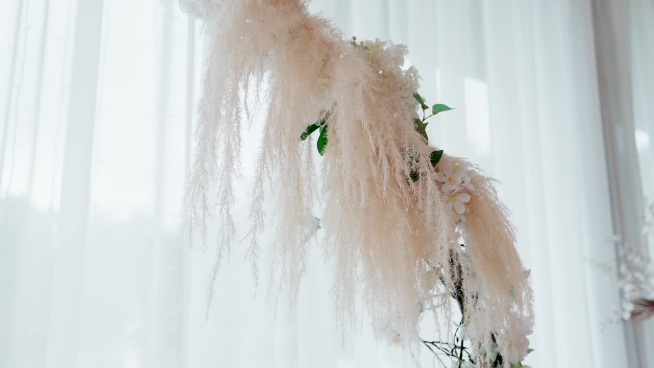 dried pampas and flowers hang from circular arch with soft backlight