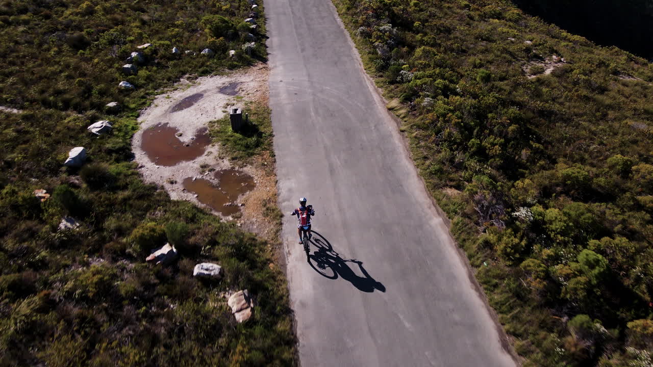 disparo de seguimiento aéreo de un ciclista en la parte superior de la unidad rotativa, carretera panorámica en la cima de la montaña