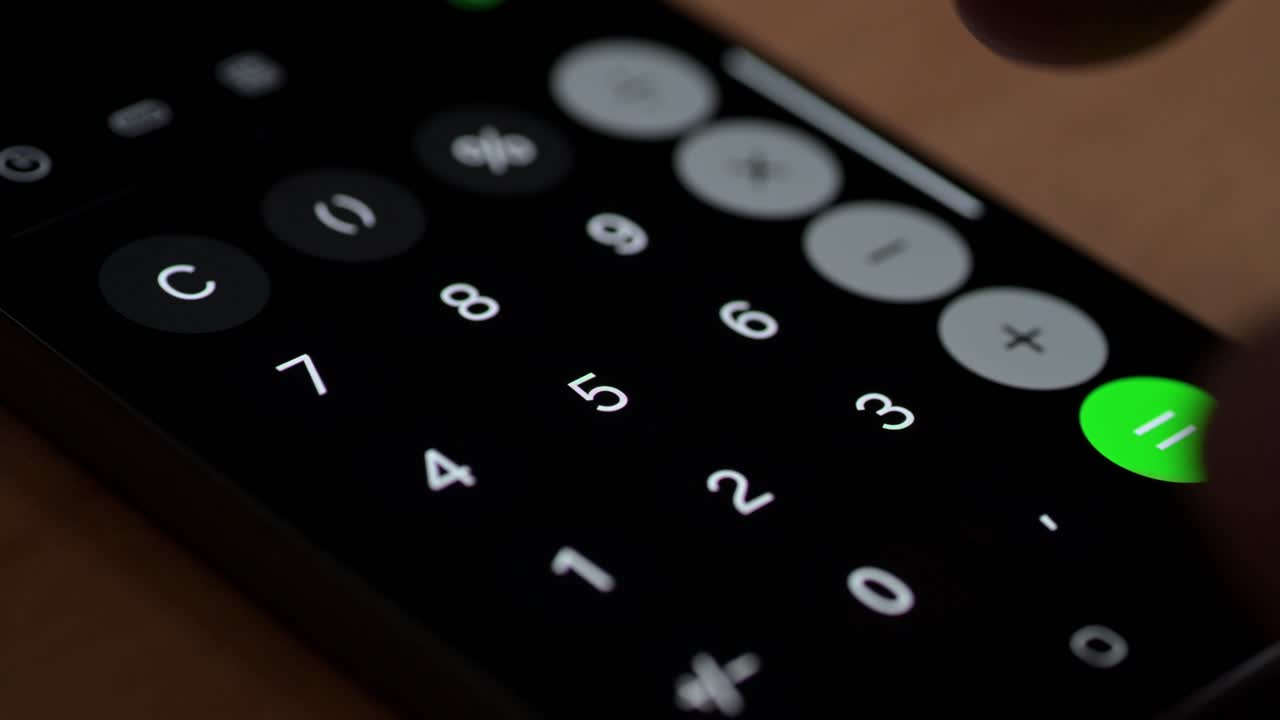 A close-up view of a hand pressing a button on a smartphone calculator app. The dark interface is illuminated by the white numeric keys and a bright green button