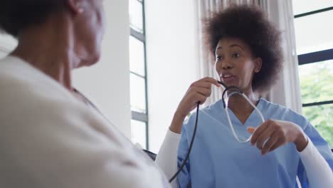 Feliz-Doctora-Afroamericana-Con-Estetoscopio-Hablando-Con-Una-Paciente-Mayor,-Cámara-Lenta