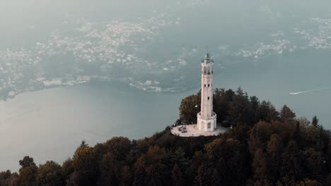 volta lighthouse on the hilltop overlooking the como lake and city on a misty morning in brunate, italy, europe