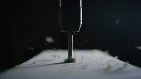 macro close up of professional carpenter working wood with drill machine in a workshop of wood factory