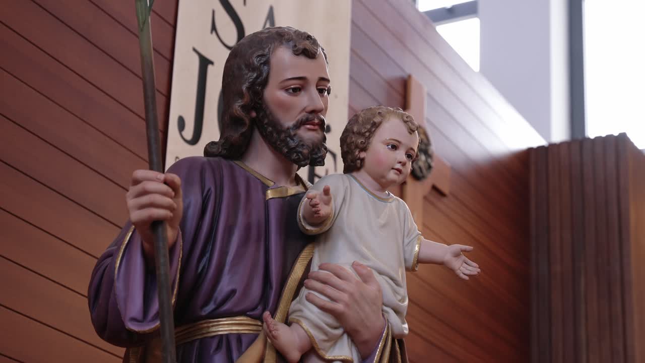 Saint Joseph statue holding baby Jesus inside a wooden-paneled church