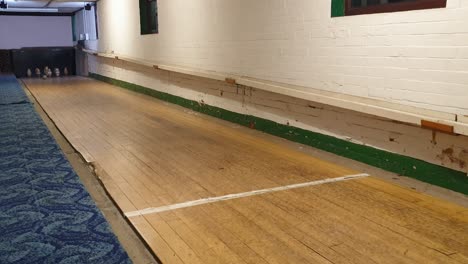 Traditional-English-pub-game-of-nine-ball-skittles-with-ball-hitting-wooden-pins-on-alley-in-Somerset,-England-UK