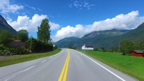 driving a car on a road in norway. in the background, the biker rides a motorcycle.