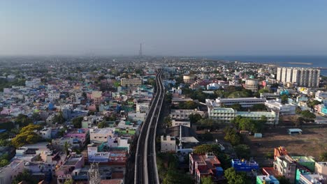 wide aerial scan of rooftops, temples, and train tracks intersecting the city