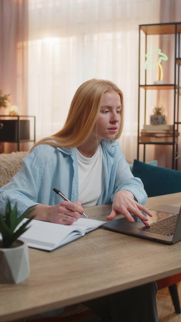 Ung kvinne studerer hjemme videobærbar leksjon fokus notater i notatbok oppmerksomt læringsøyeblikk