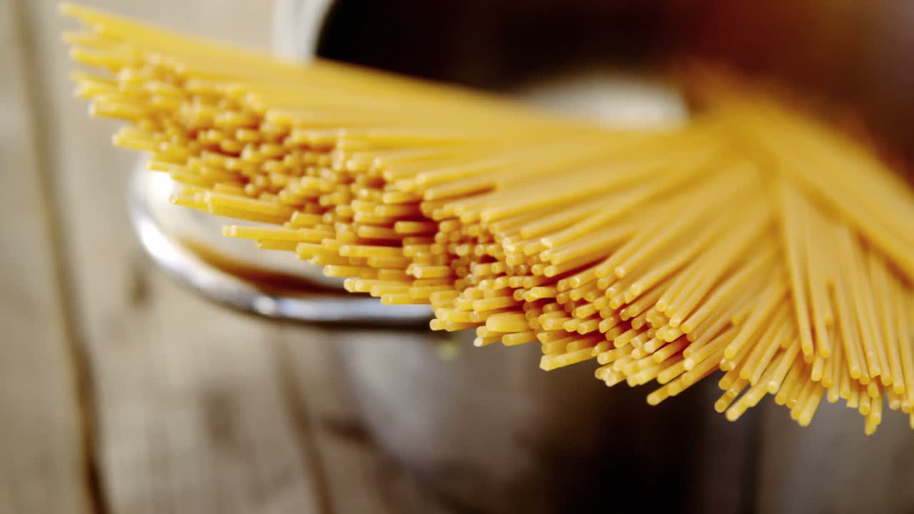 espagueti crudo dispuesto en una olla de plata listo para ser cocinado en una mesa de madera