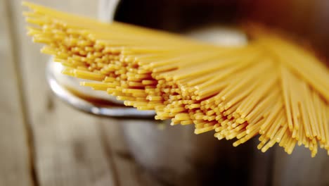 espagueti crudo dispuesto en una olla de plata listo para ser cocinado en una mesa de madera