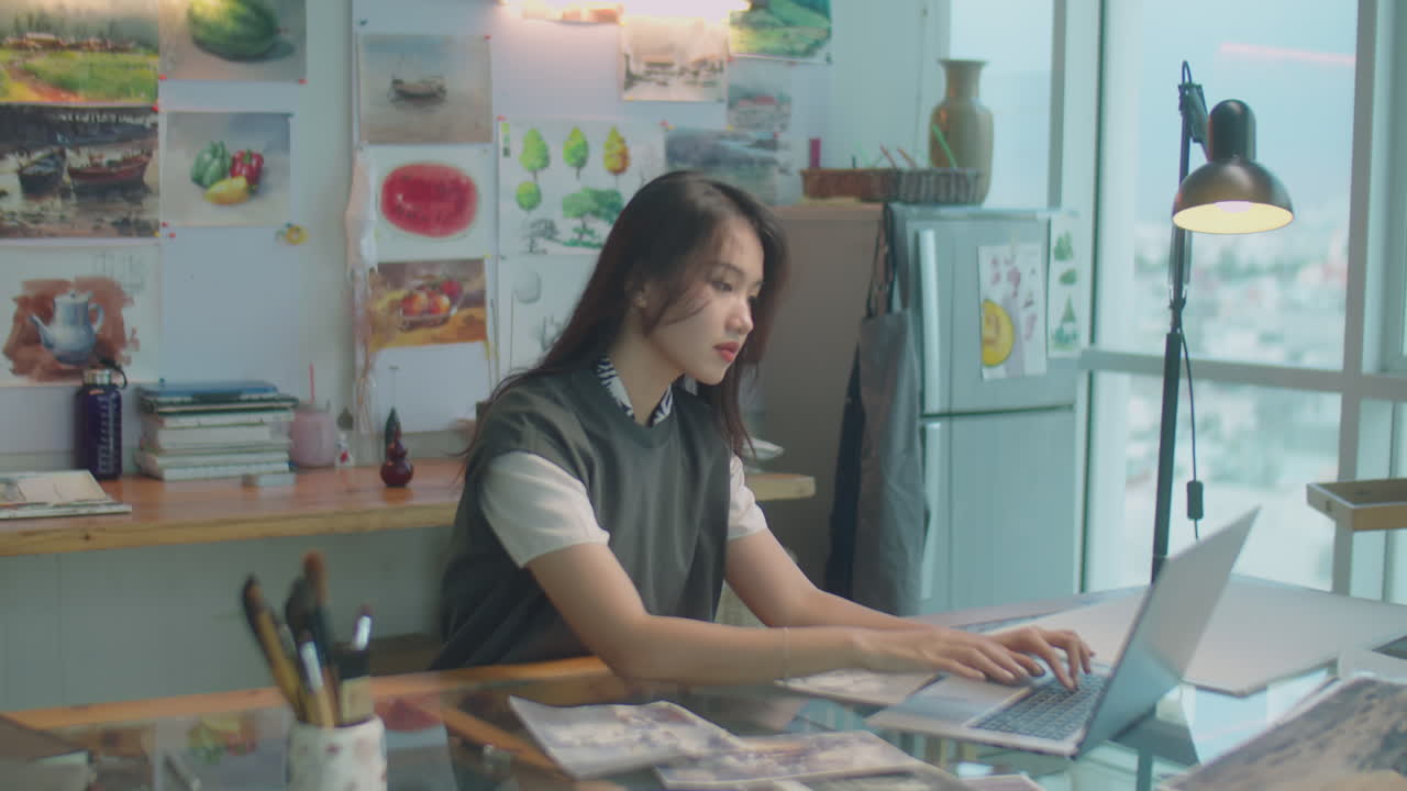 Asian Woman Working with Drawings and Laptop in Art Studio
