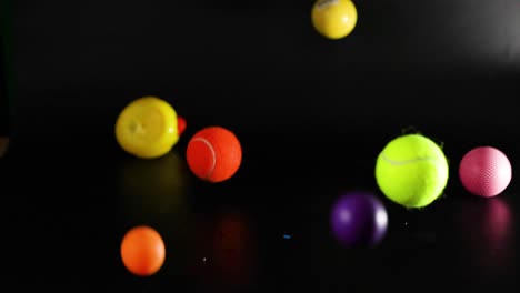 various balls bouncing and rolling on black surface