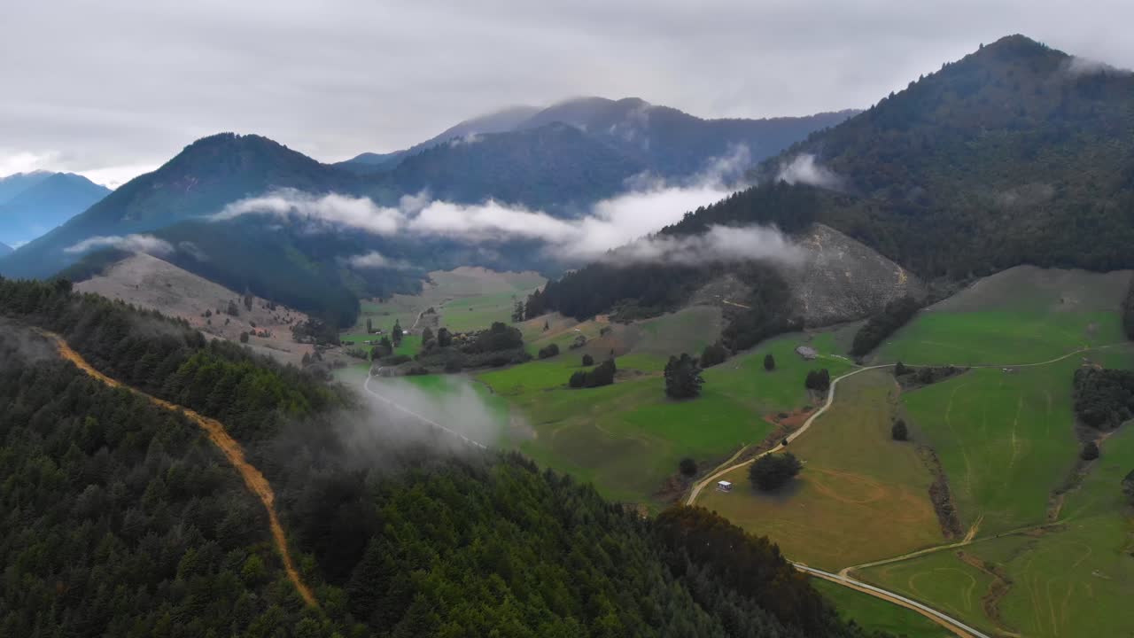 vista aérea de un valle rural, mostrando pequeñas nubes blancas entre montañas en marlborough, nueva zelanda