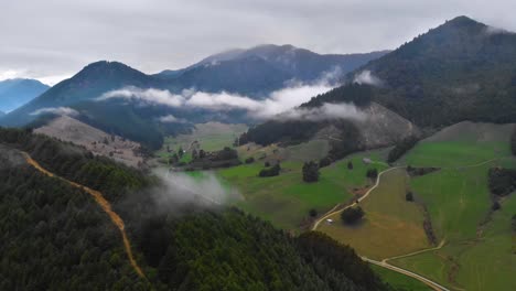 Aerial-view-of-a-rural-valley,-showing-small-white-clouds-between-mountains-in-Marlborough,-New-Zealand