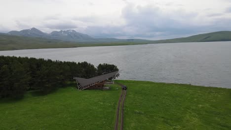 una vista de un lago sereno rodeado de campos verdes exuberantes y montañas lejanas bajo un cielo nublado en georgia