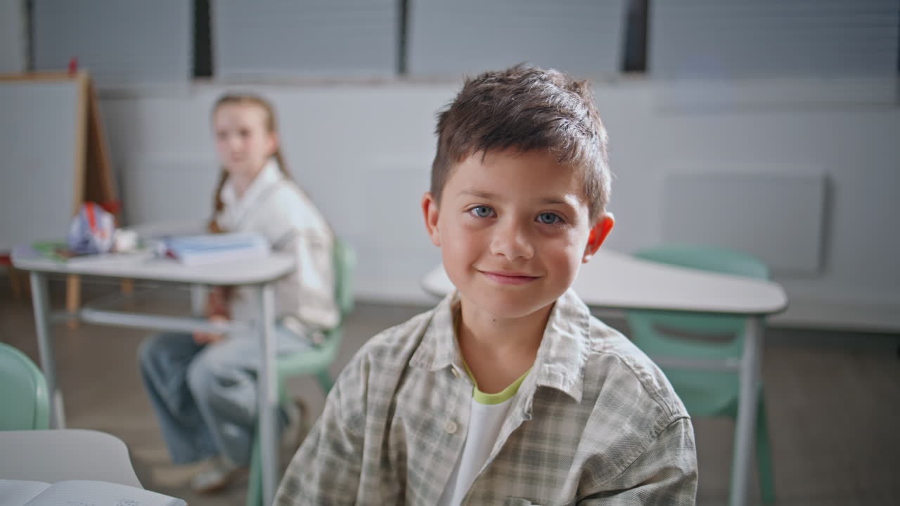 Portrait smart pupil studying at elementary school. Positive boy raising hand