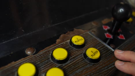 un hombre presiona un botón del jugador en una máquina recreativa