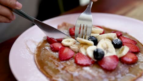 cutting a strawberry banana pancake