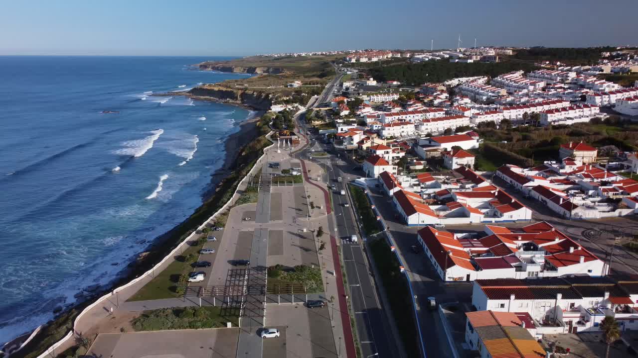 toma aérea ascendente de casas frente al mar de ericeira, olas del océano rompiendo en la orilla