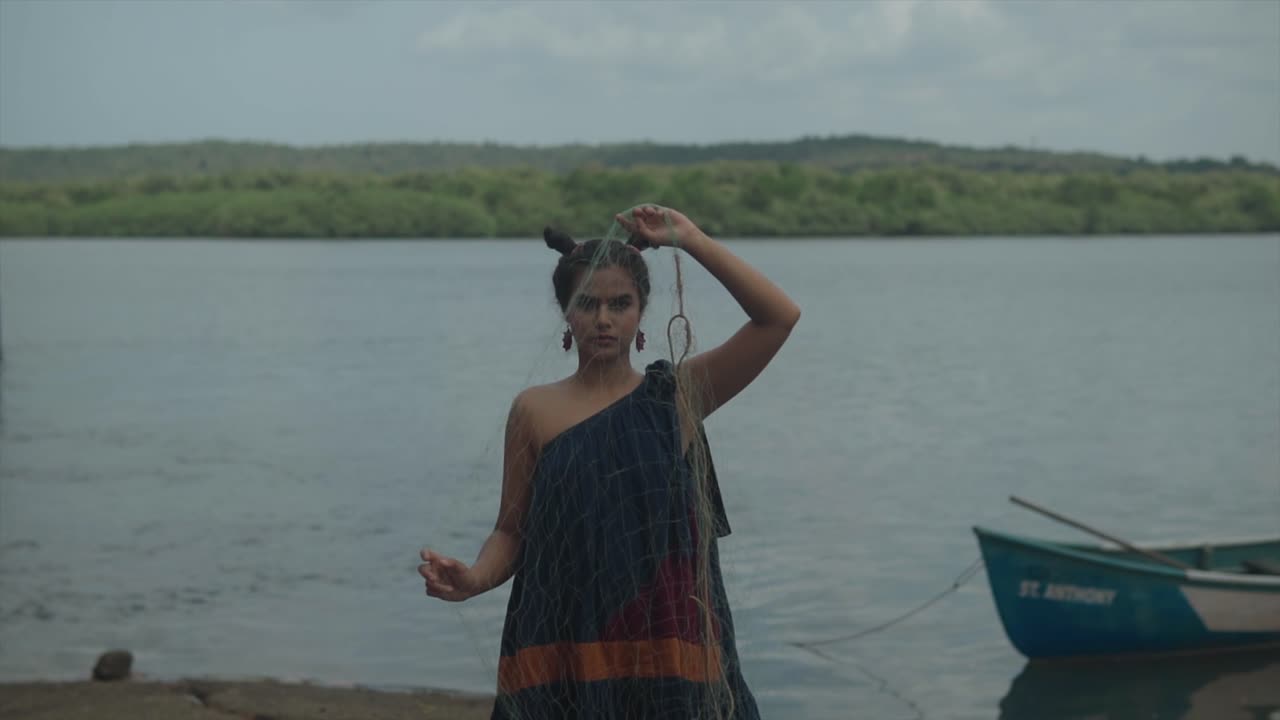 Close-up of a concerned woman's face, revealing the littered beaches and disregard for nature, including discarded fishing nets with ocean behind her