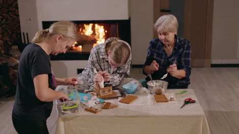 familia decorando una casa de pan de jengibre junto a la chimenea