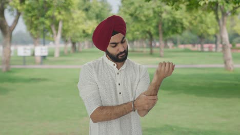 sick sikh indian man suffering from hand pain in park