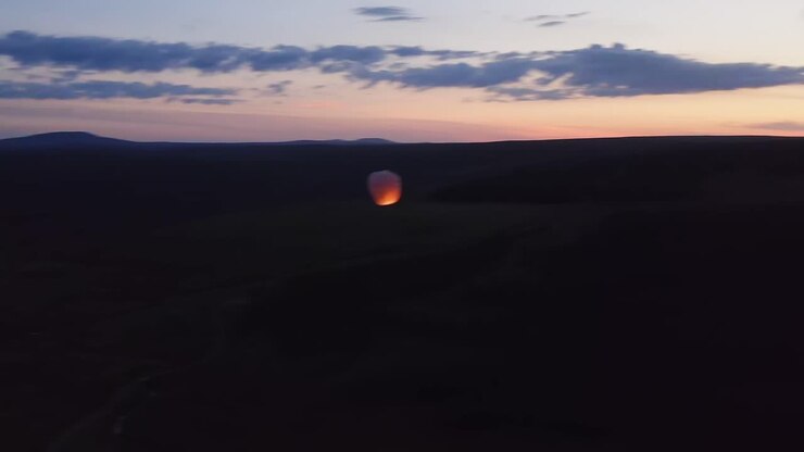 Drone shot at dusk of a sky lantern over peatland on the Isle of Lewis