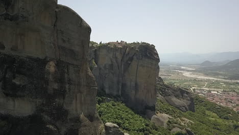 vertical cliff aerial reveals medieval monastery on top of rock cliff