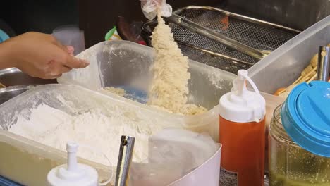 preparing fried food at a street food stall