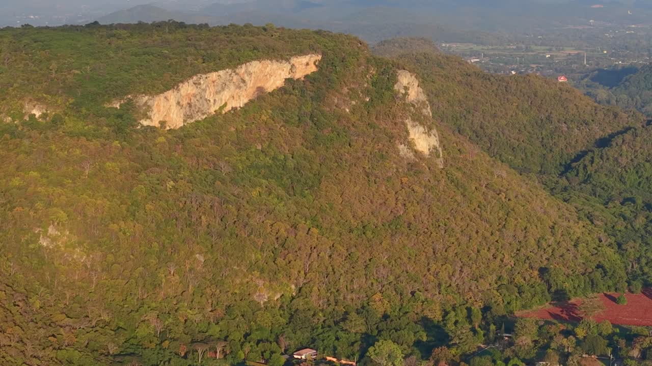 Rekaman drone menangkap gunung hutan tropis yang rimbun dengan tebing batu yang menonjol saat matahari terbenam