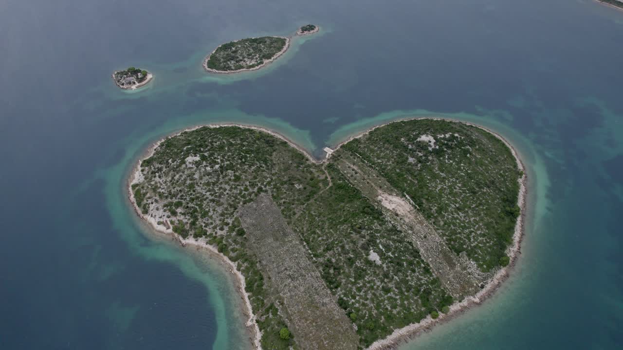 Dronekuva romanttisesta, sydämenmuotoisesta Love Islandista auringonlaskun aikaan, Kroatia