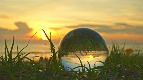 the sunset in a crystal ball placed on the grass.