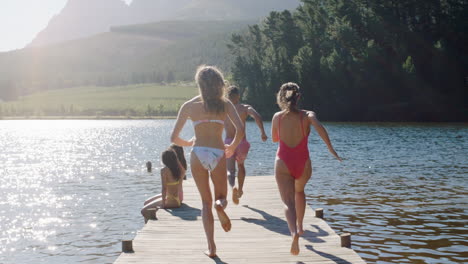 group of friends running jumping off jetty in lake at sunset having fun splashing in water enjoying freedom sharing summertime adventure