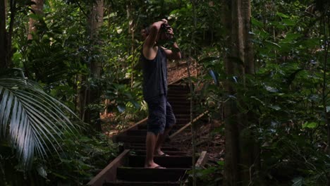 static shot of a traveling photographer standing on a wooden staircase in the jungle while taking spectacular shots of nature during an adventurous trip from norfolk island to the botanical garden