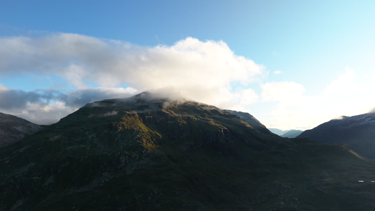 Aerial view of Swiss Alps peaks under a serene cloudy sky at sunrise