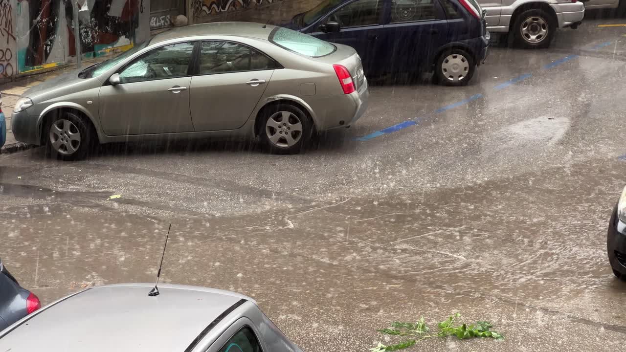 fuertes lluvias en la ciudad con agua de lluvia corriendo por la calle asfaltada con autos estacionados