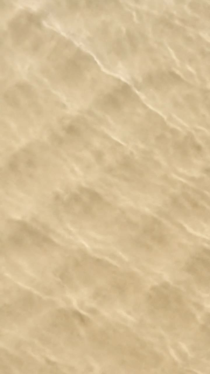 Vista aerea di dolci onde oceaniche che creano un motivo strutturato sulle rive sabbiose, perfetto per un effetto calmante