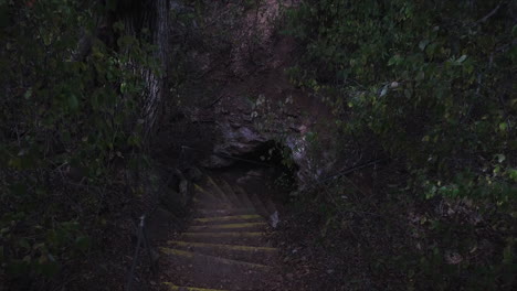 ascending shot of steps leading down into a deep dark cave