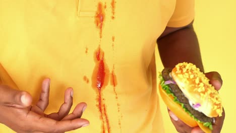 hombre comiendo hamburguesa, mancha de ketchup en la camisa