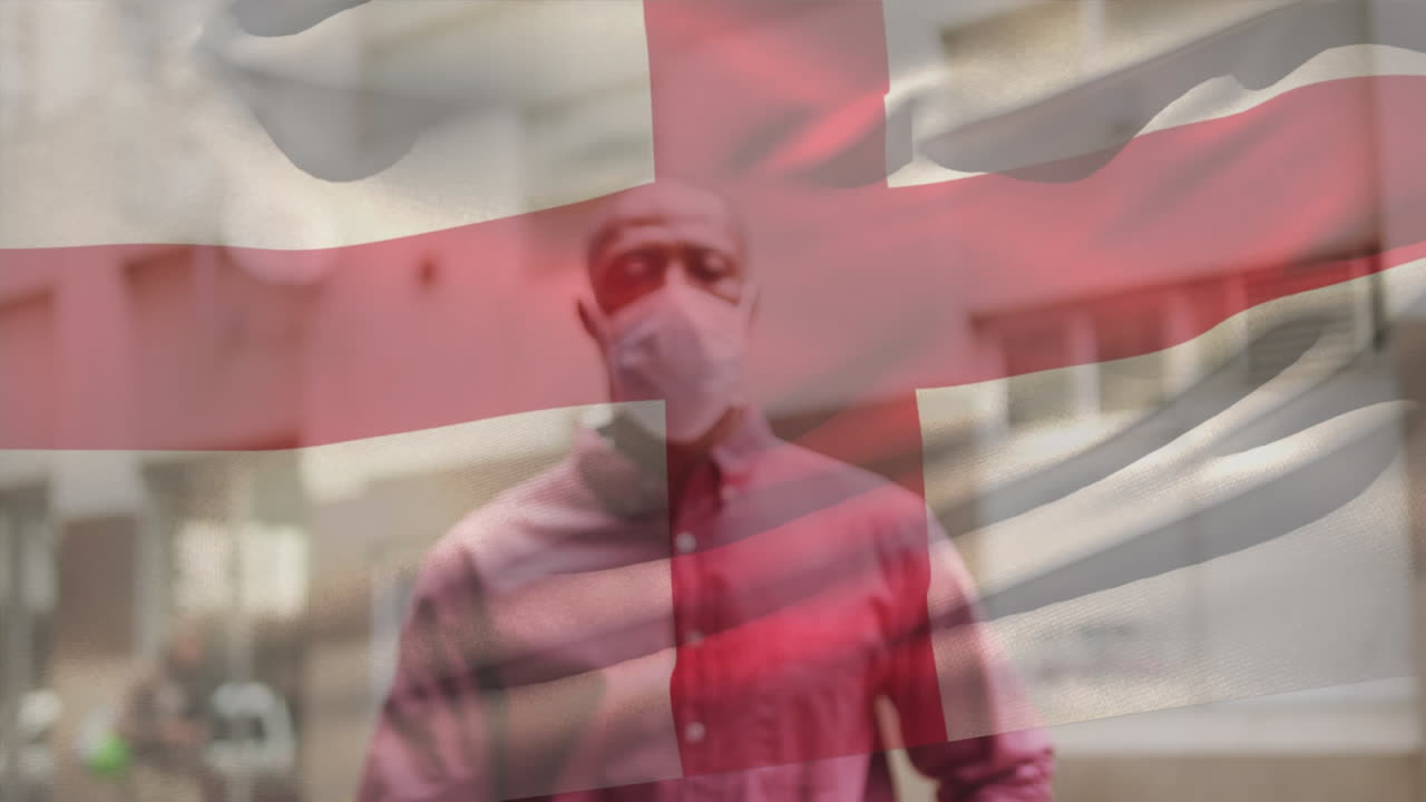 animación de la bandera de inglaterra ondeando sobre un hombre afroamericano con máscara facial en la calle de la ciudad