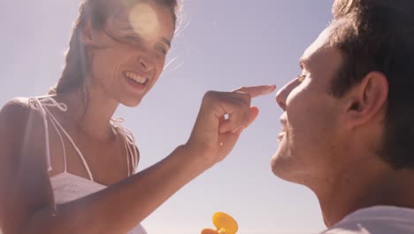 Woman-putting-sunscreen-to-her-boyfriend-